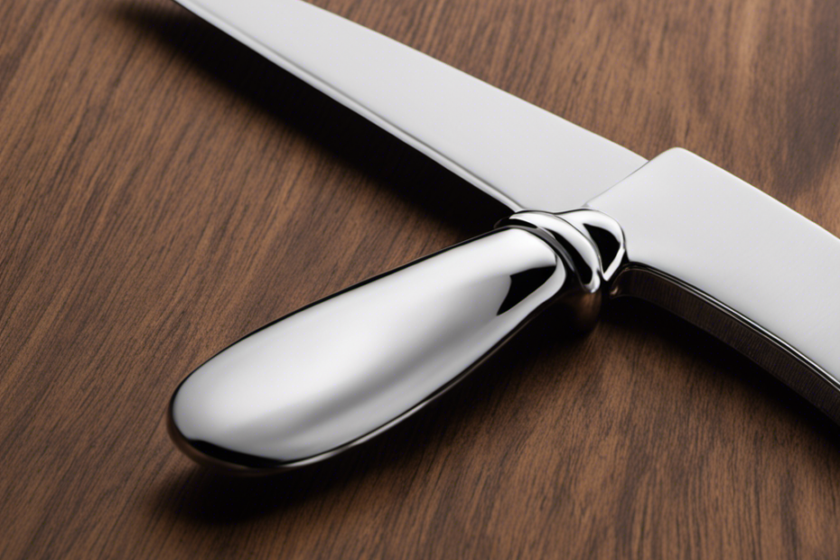 An image showcasing a close-up view of a silver butter knife resting on a wooden cutting board, highlighting its smooth, rounded edges, its sleek, elongated shape, and the subtle gleam reflecting off its surface