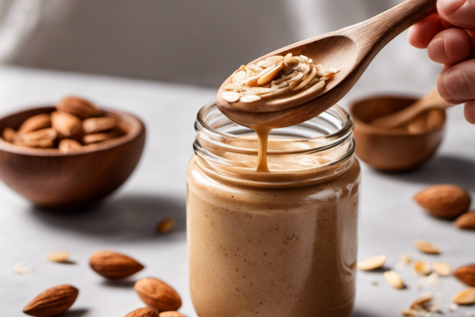-up image of a hand holding a wooden spoon, gently swirling smooth almond butter in a glass jar